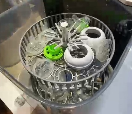 The rotating basket loaded with bottles, teats and pacifiers